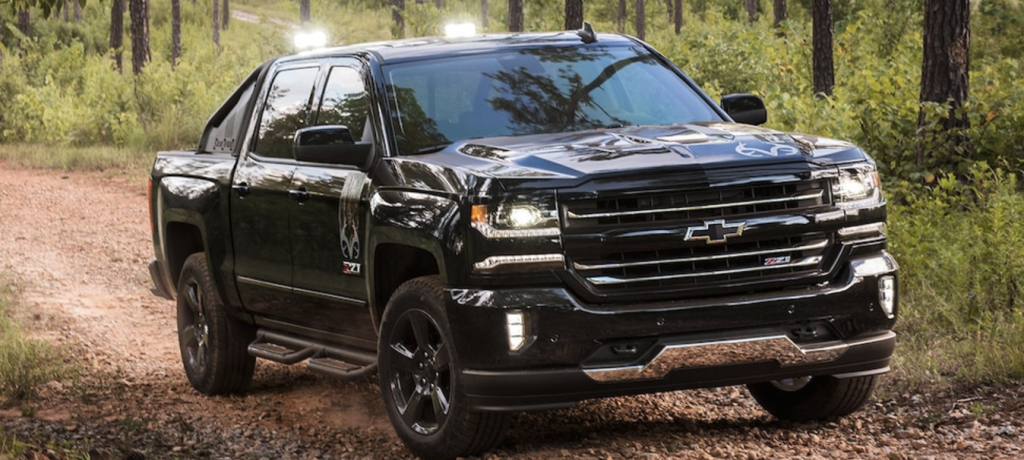 A black Chevy Silverado Realtree driving through the woods
