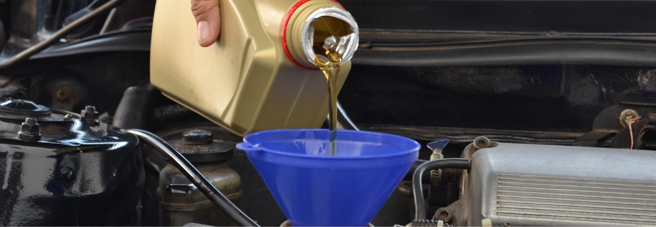 Auto mechanic pouring motor oil into a car engine