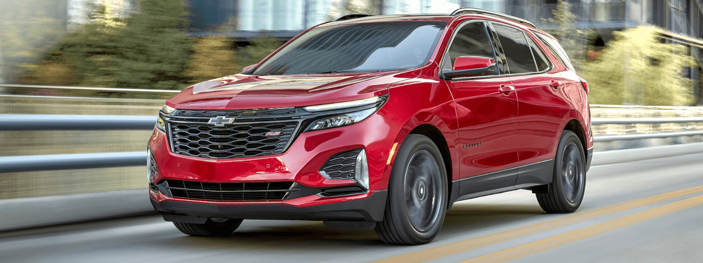 New Red 2024 Chevy Equinox Driving through an urban road
